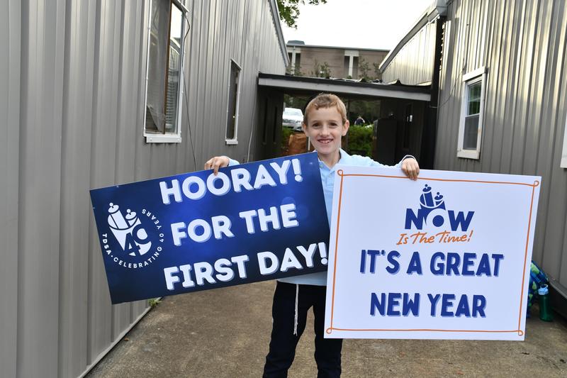 A student poses with a sign on the first day.
