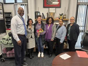 Kelly Walsh holds flowers surrounded by school and district leaders