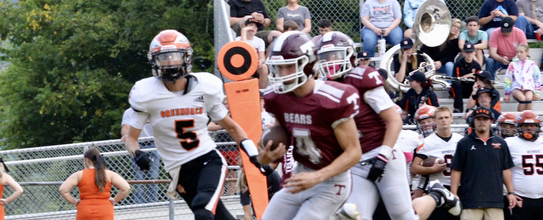 Football game scene with players, spectators, and goalpost.