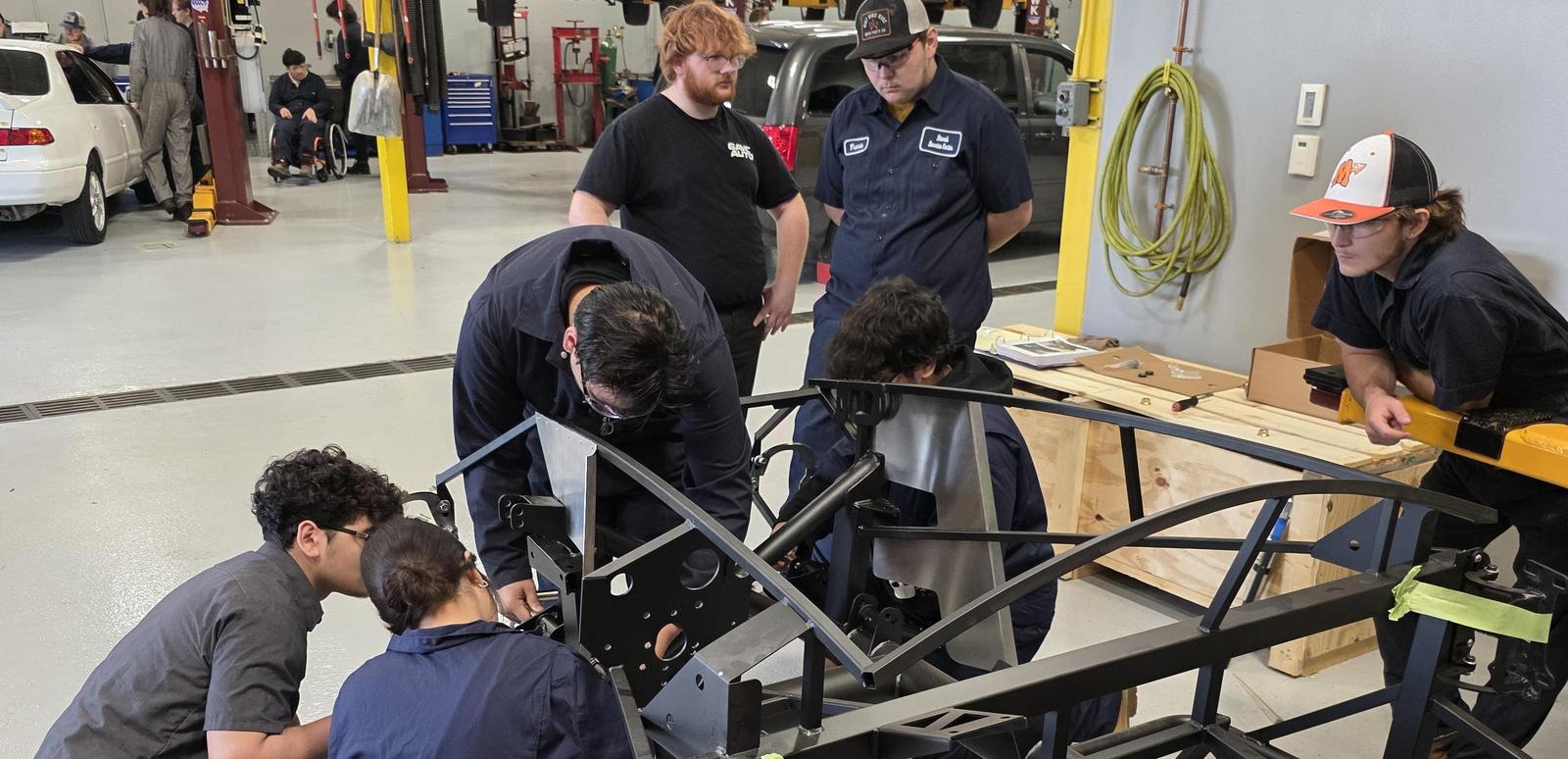 Automotive students work on the frame of the kit car.