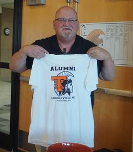 An alumni officer holds up the new t-shirts for sale.
