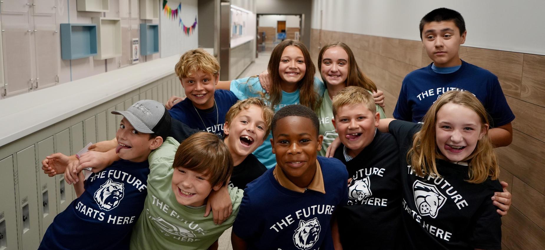 Group of children smiling together in a school hallway.