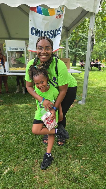 A mother and daughter pose in front of the concessions stand with their arms around each other