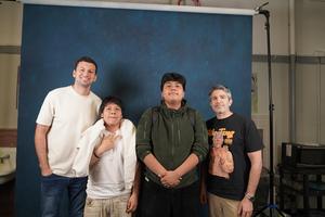 Four individuals posing together in front of a blue backdrop.