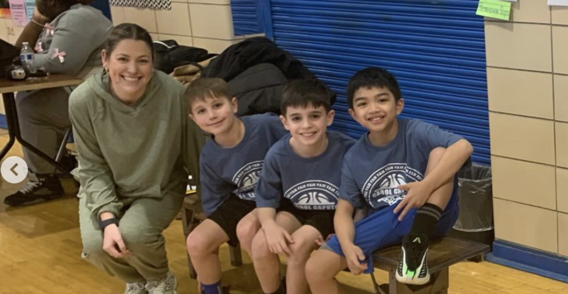 Four children and an adult pose happily in a gym environment.