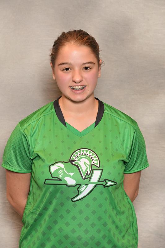 female athlete poses with arms behind her back in front of grey backdrop