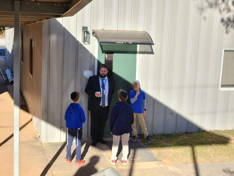 Three fifth grade boys discuss a clue with Rabbi Pollock.