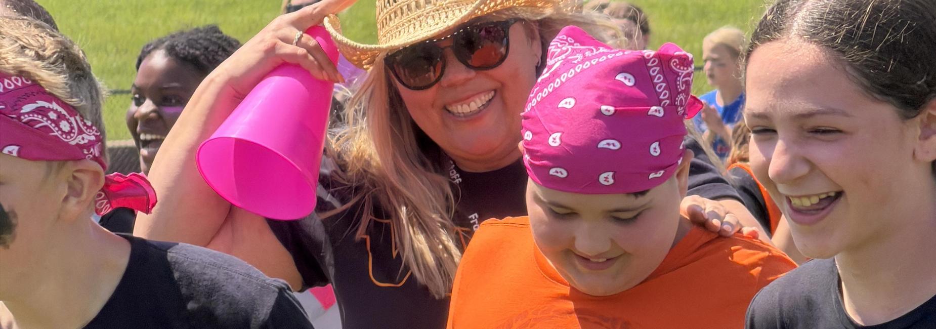 Group of smiling individuals at an outdoor event wearing colorful bandanas.