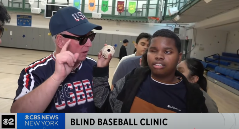a man in a baseball uniform is holding a baseball with a young boy during a news interview