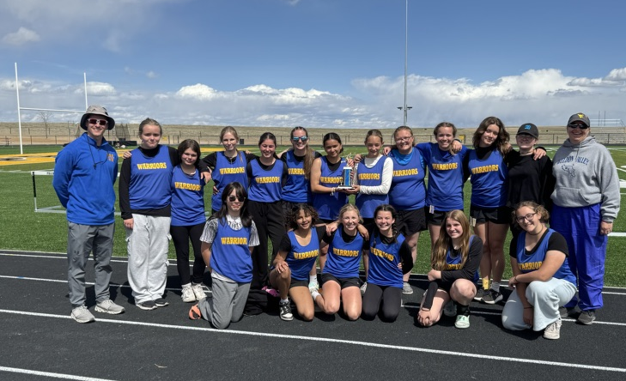 Group of track and field athletes in blue uniforms posing together on a track.