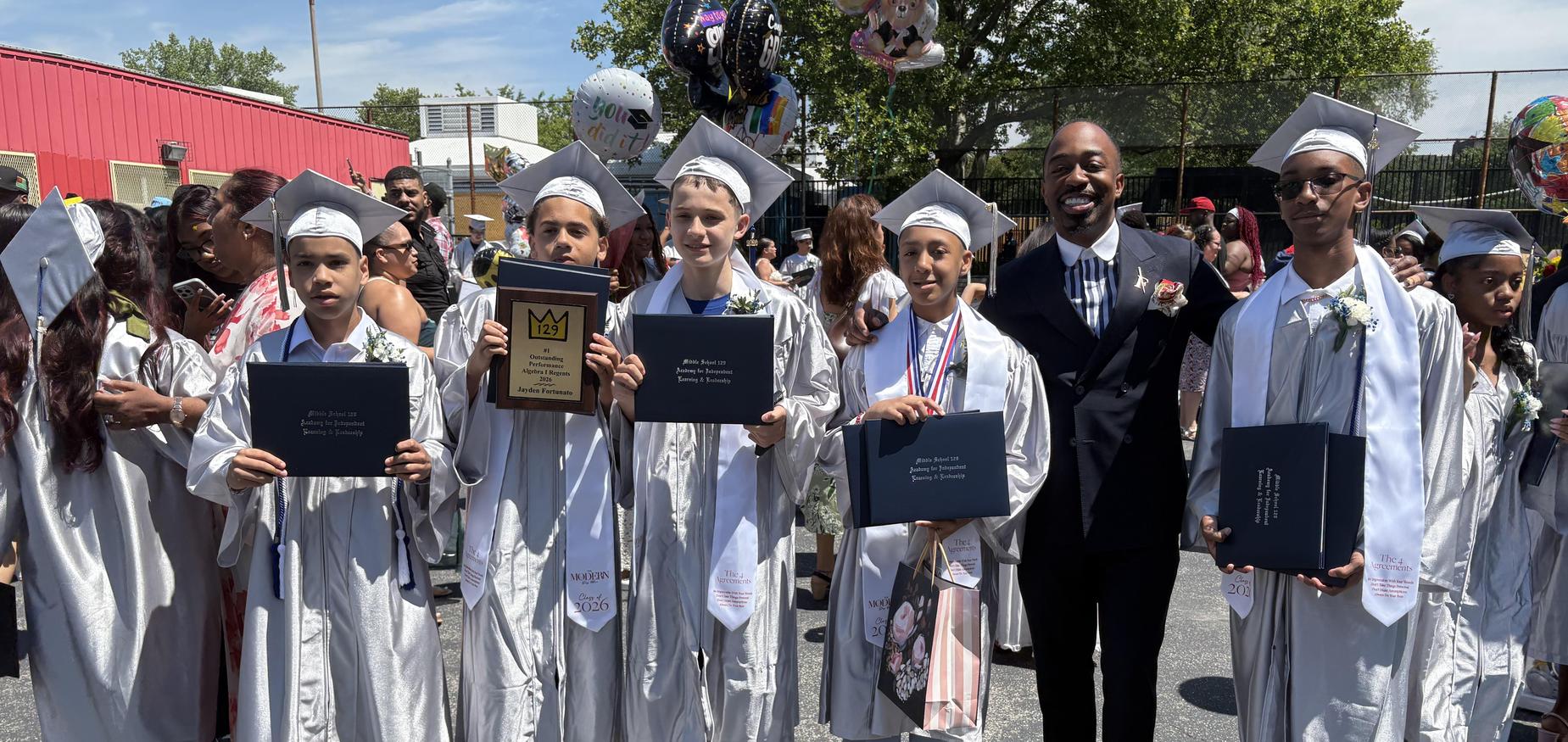 Graduating students from the modern day man program holding their diploma cases