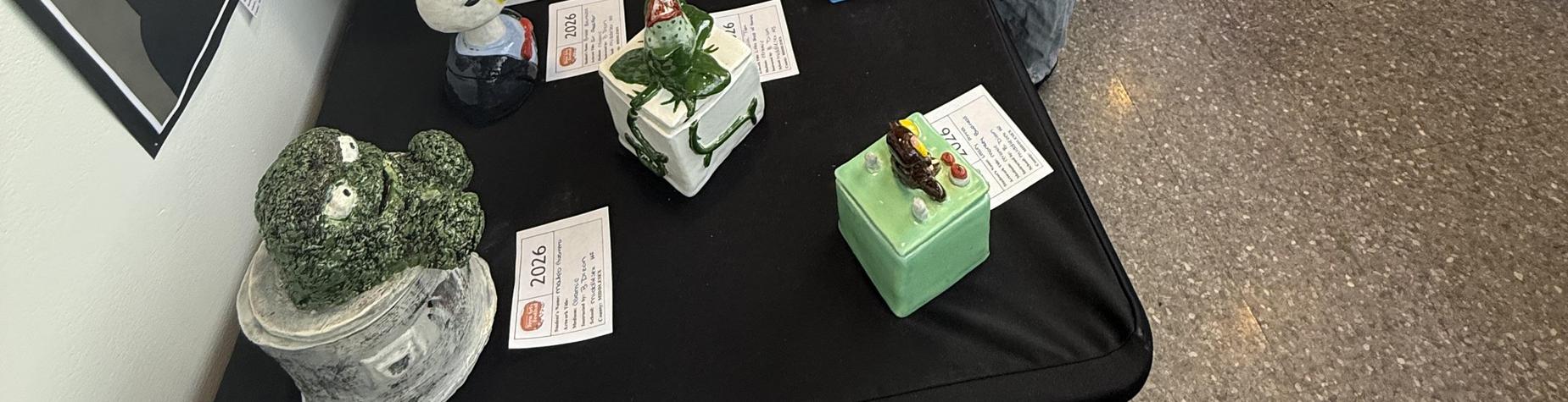 Artistic ceramic sculptures displayed on a black table with labels.