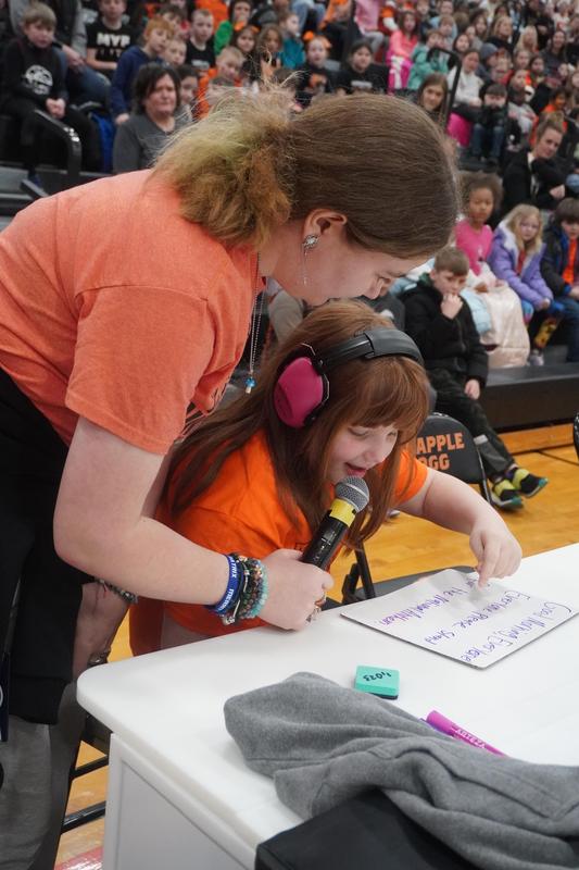 A student in the ASD class uses the microphone to welcome guests to the game.