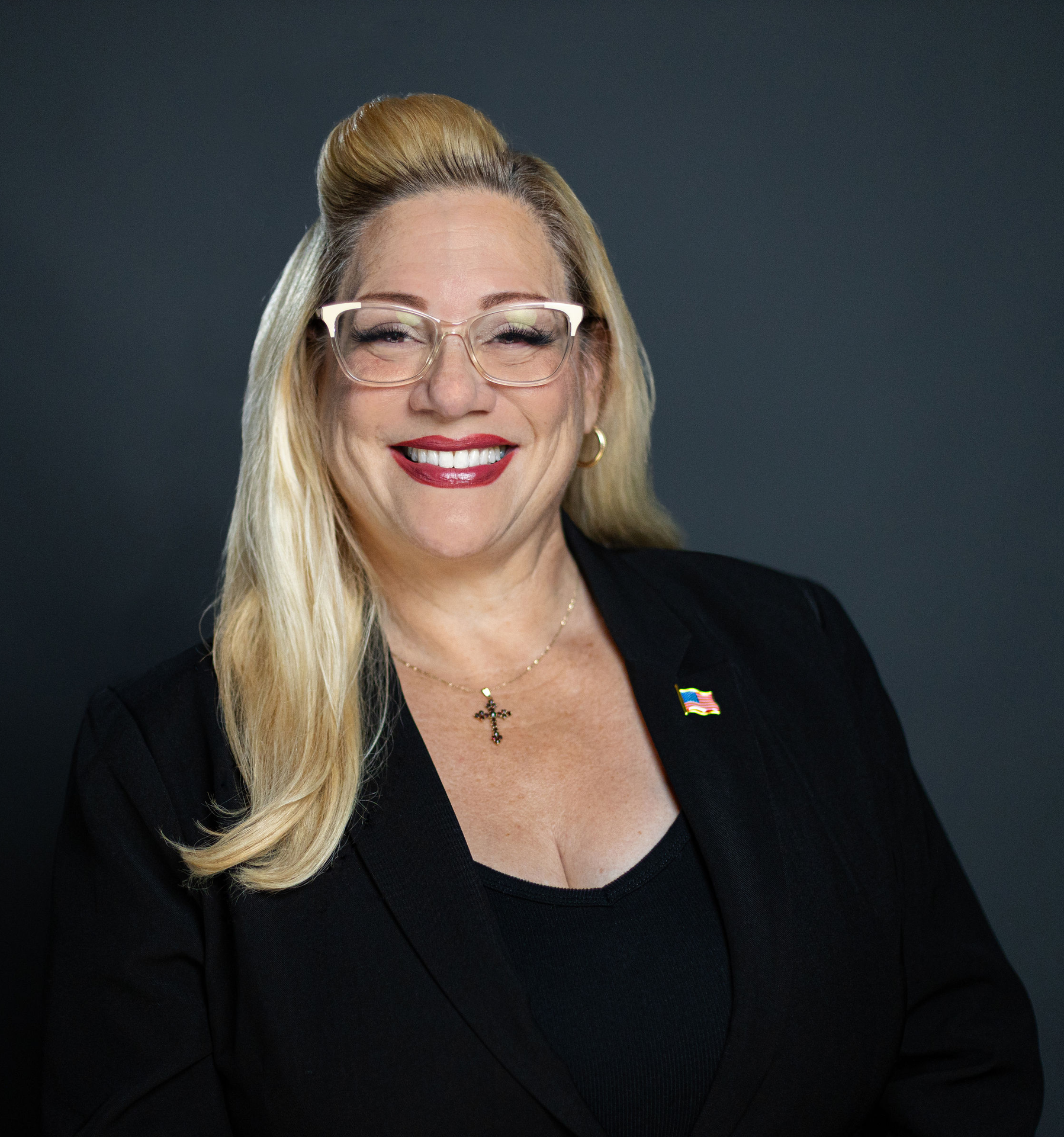 Woman with blonde hair smiling in a black top.