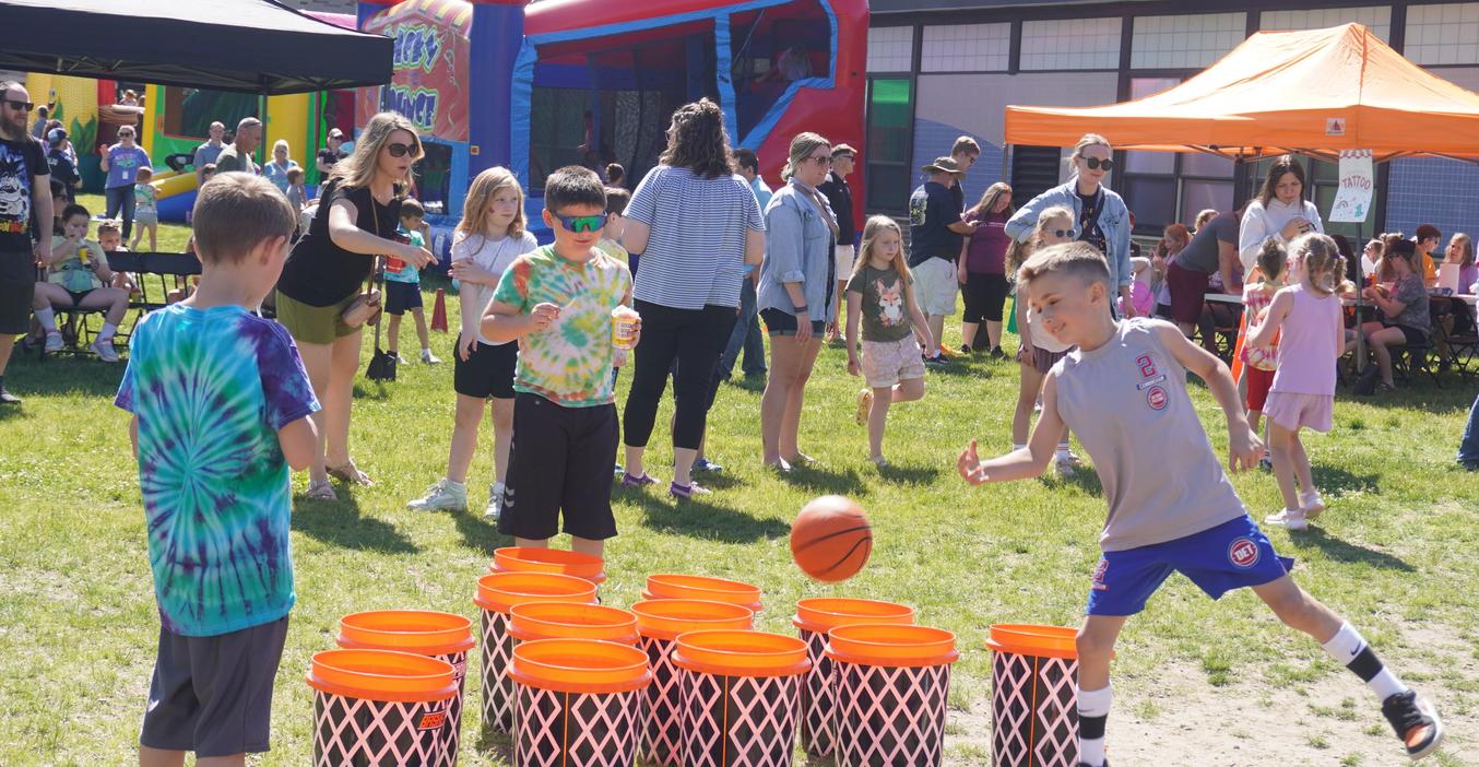 Children playing a basketball game at a lively outdoor event.