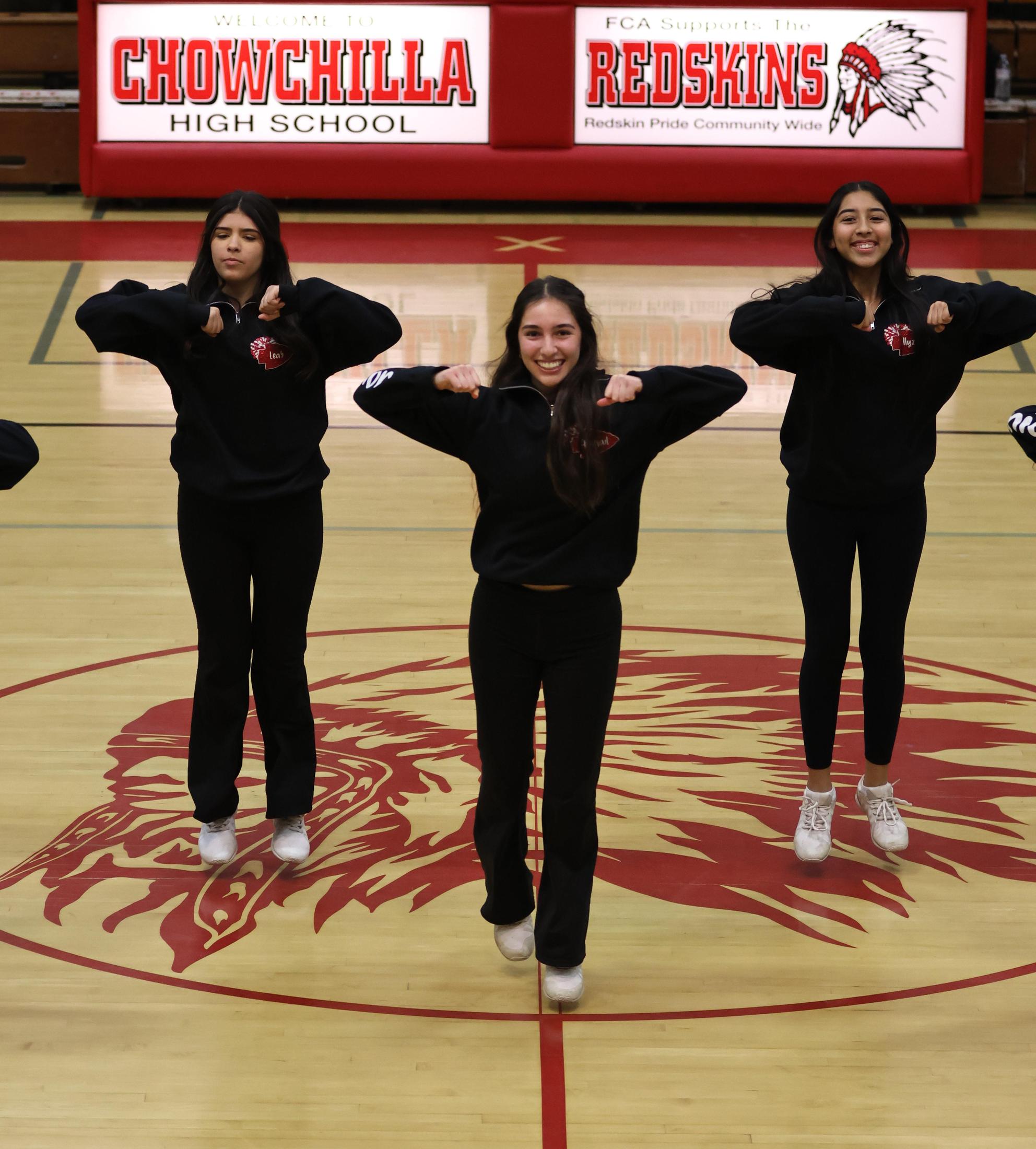 Varsity girls cheering at a basketball game against Mariposa