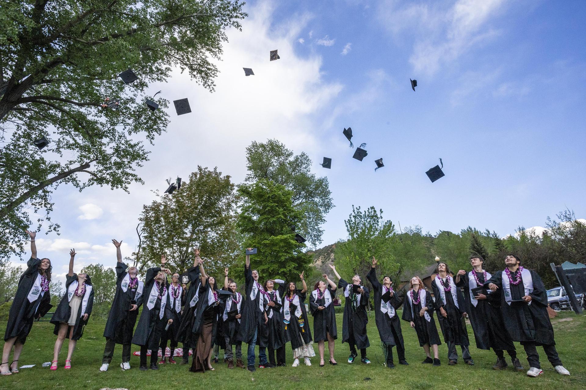 Graduates throw their caps into the air