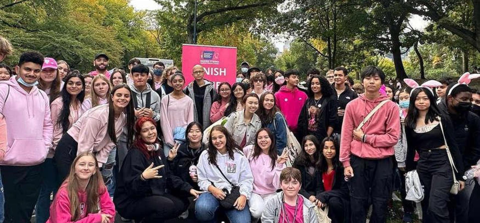 Group of diverse people in pink attire posing with a 'Finish' sign.