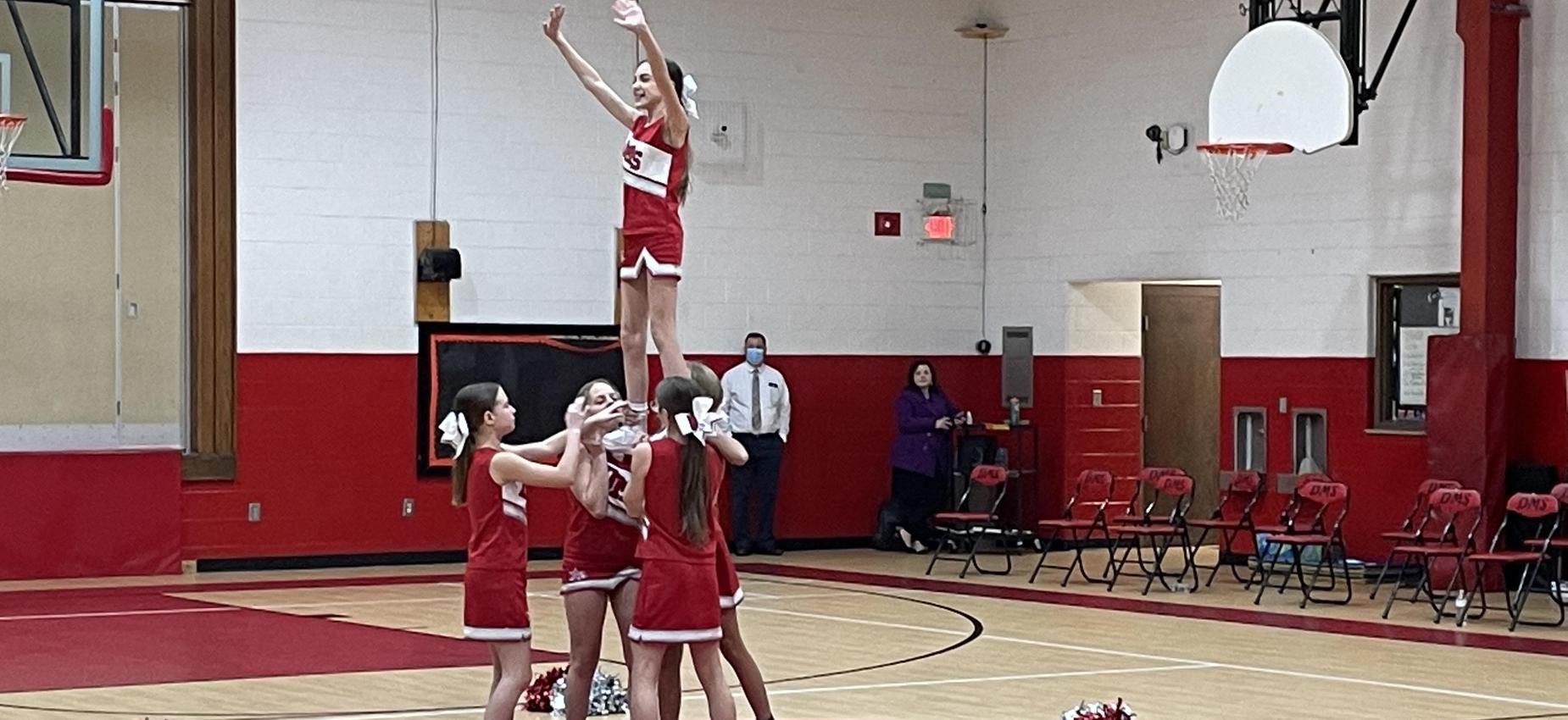 Cheerleaders do a stunt in a gym.