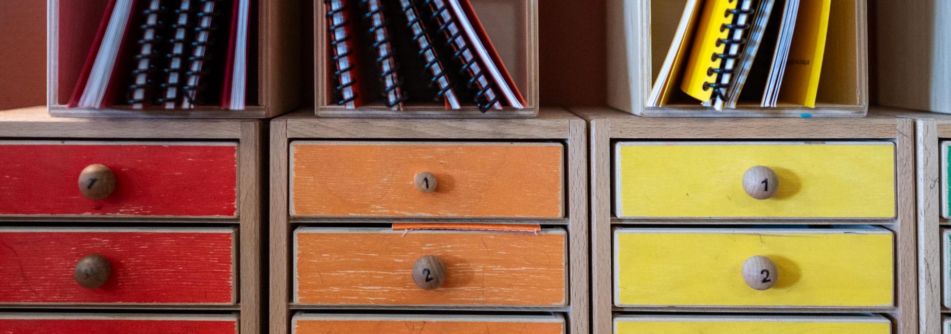 Colorful drawers with wooden knobs in a storage unit.