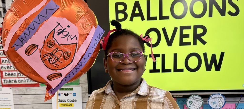 smiling girl holds a decorated balloon