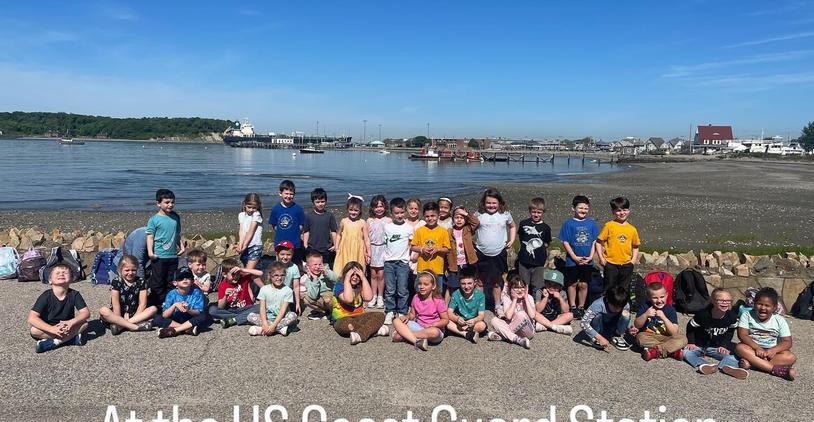 Group of children at the US Coast Guard Station smiling by the waterfront.