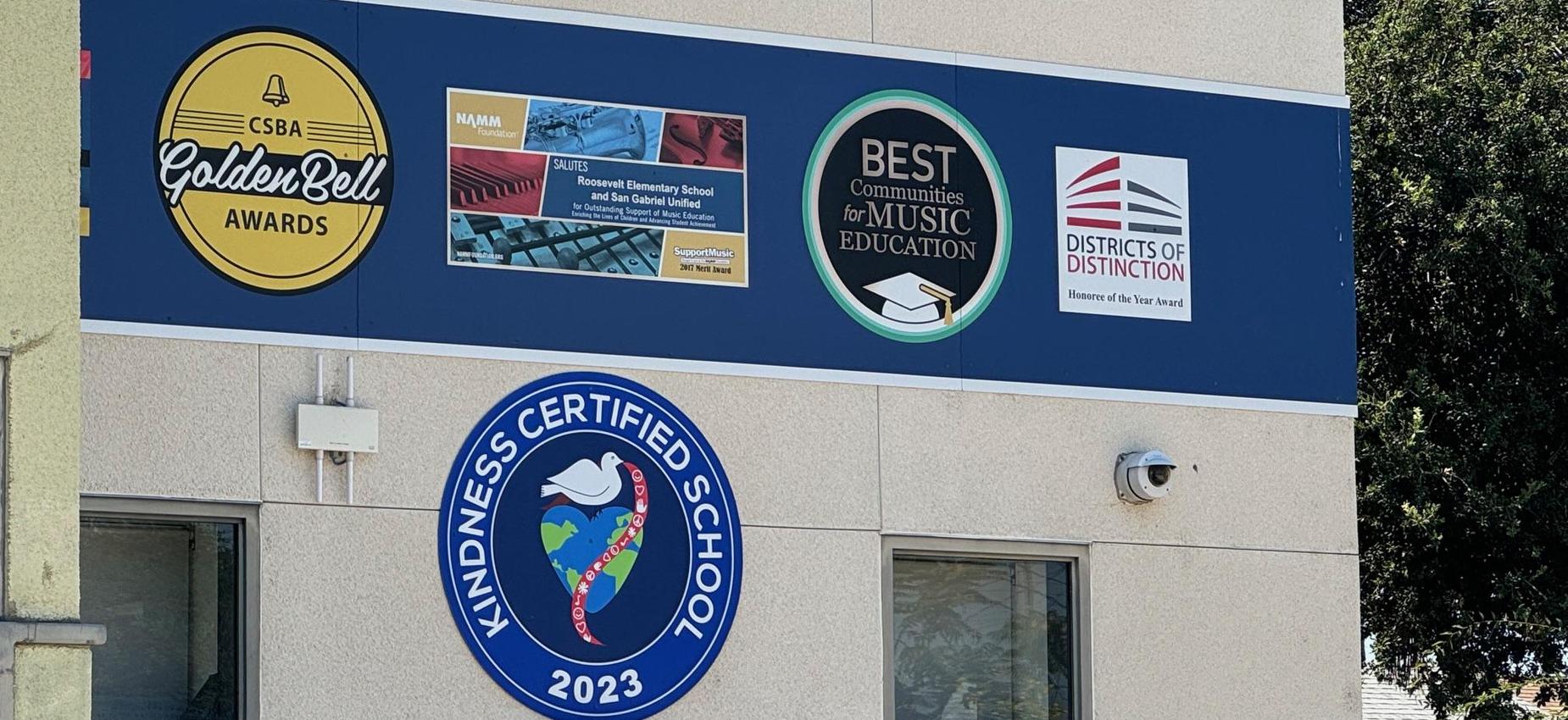 Wall featuring awards, music education recognition, and kindness certification.