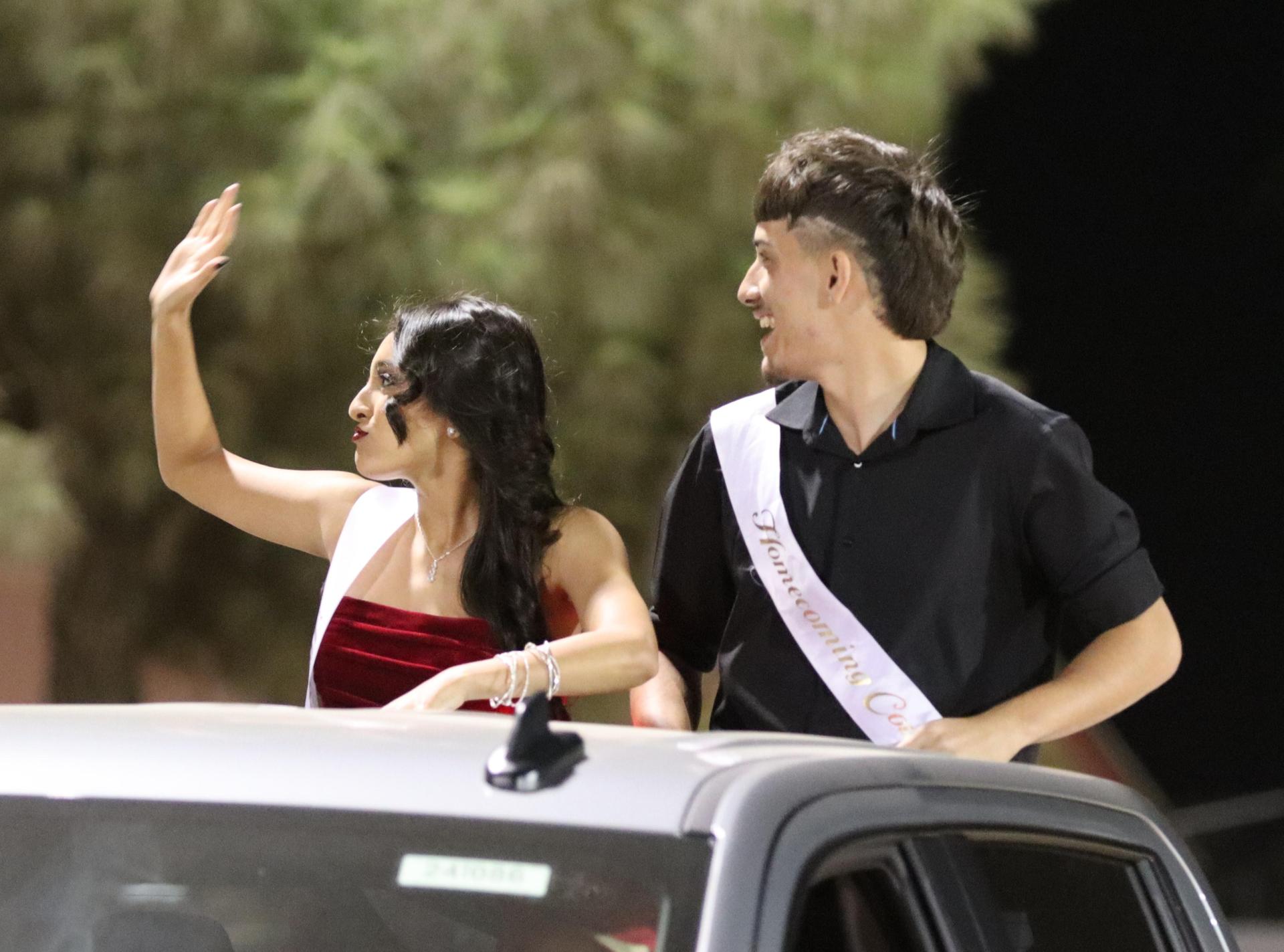 homecoming king and queen candidates entering the stadium in trucks