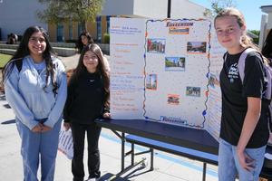 three students standing by a Cal State Fullerton College display they made