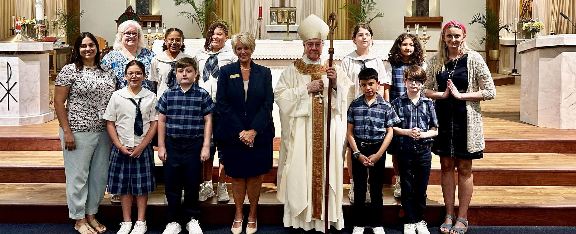 Group of people including clergy and children in a church setting.