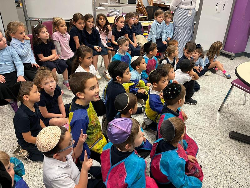 Kitah K students watch as Rabbi Rubin makes a honey dipper.