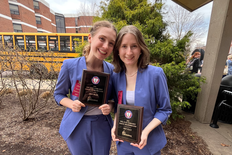 two students holding state champion plaques