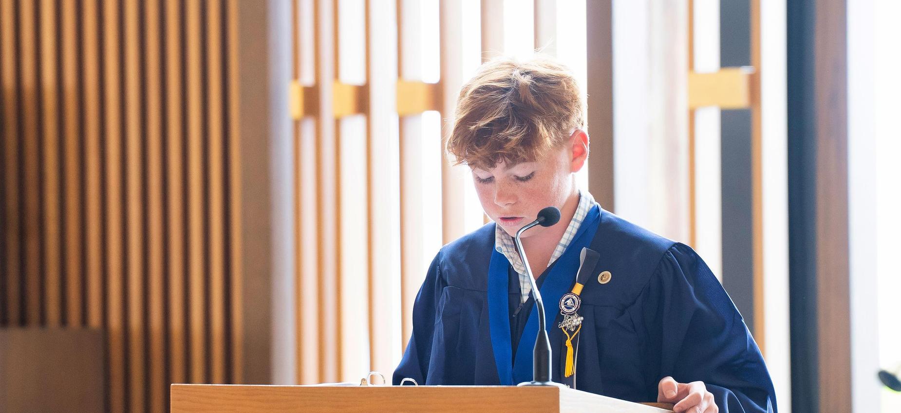 8th grade graduate reads at graduation mass
