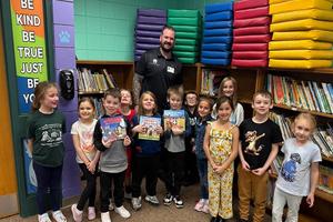 Scott Watkins (back) with a group of 1st-graders who are holding up some of his published books