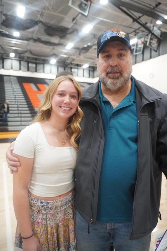 A high school student stands with her grandfather after the program.