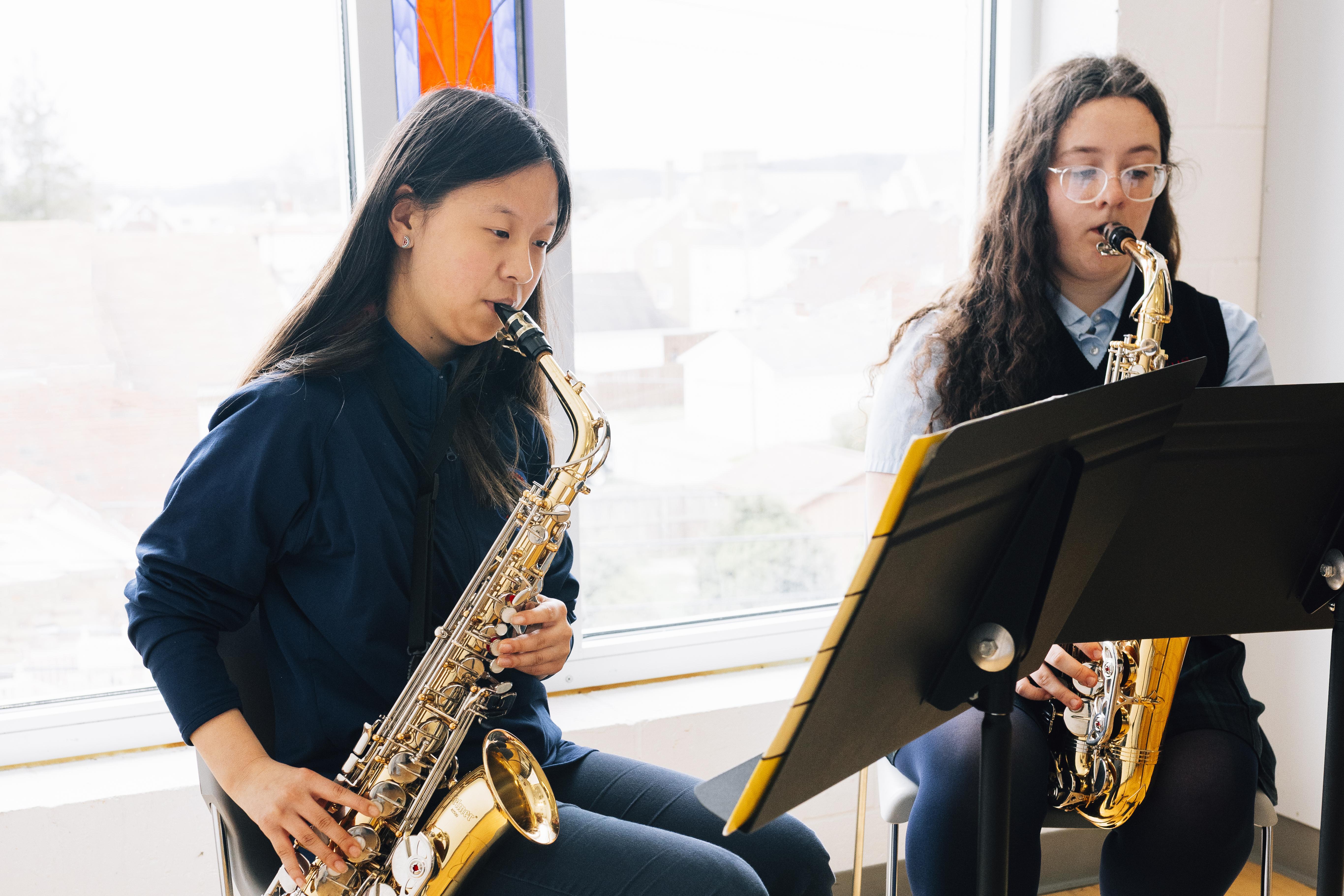 Two girls playing the saxophone.