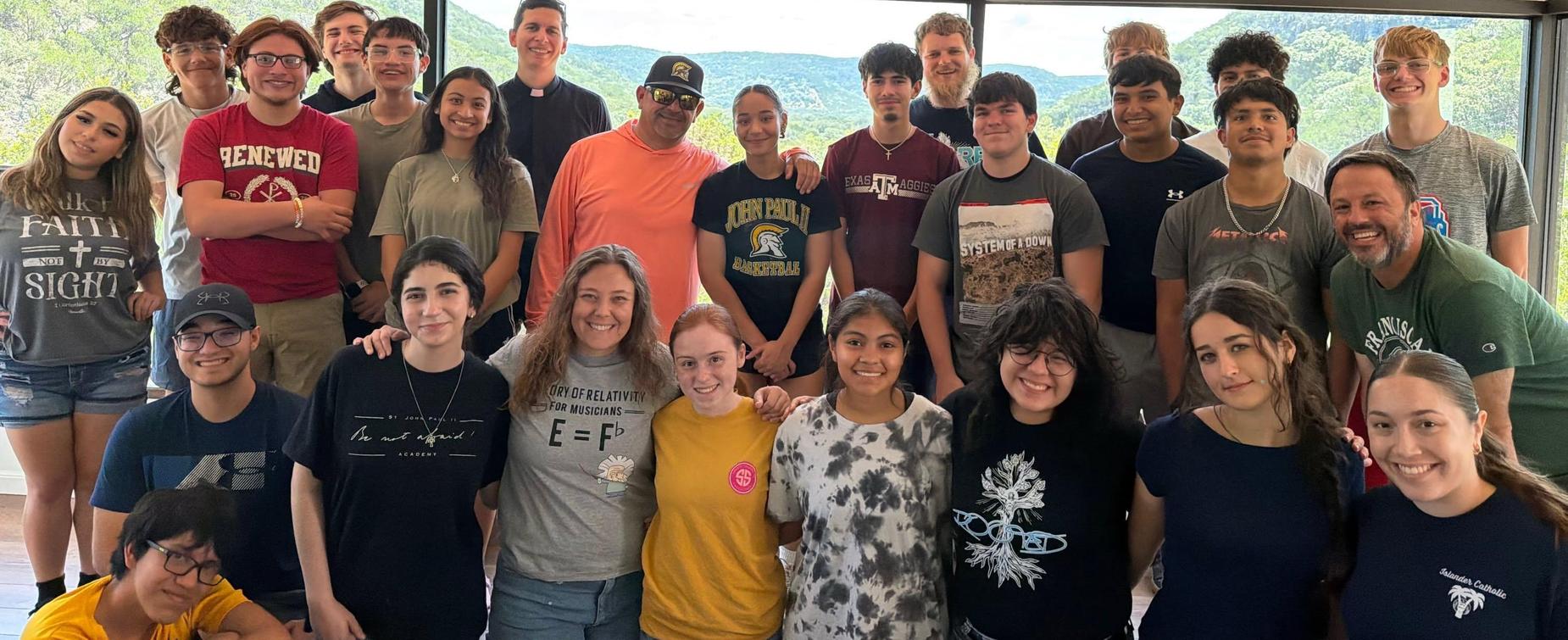 Group photo of diverse individuals smiling with a scenic mountain view in the background.