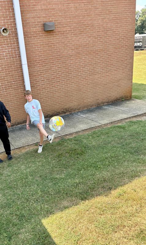 another picture of boy kicking ball up the hill