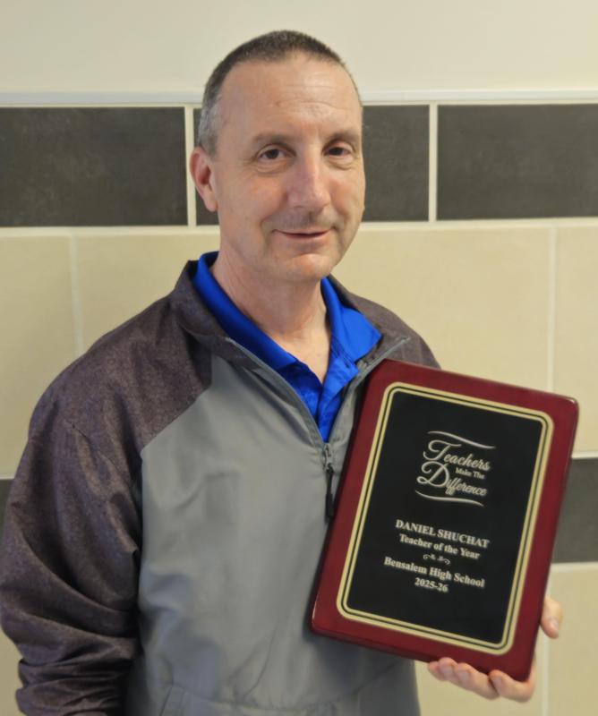 Image of a man holding his teacher of the year plaque