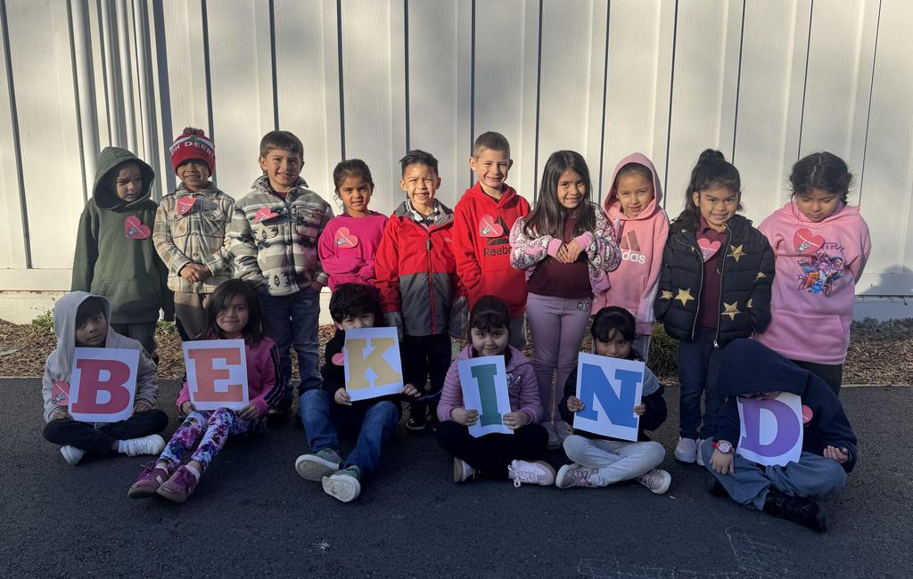 Kids holding letters to make the work BE KIND