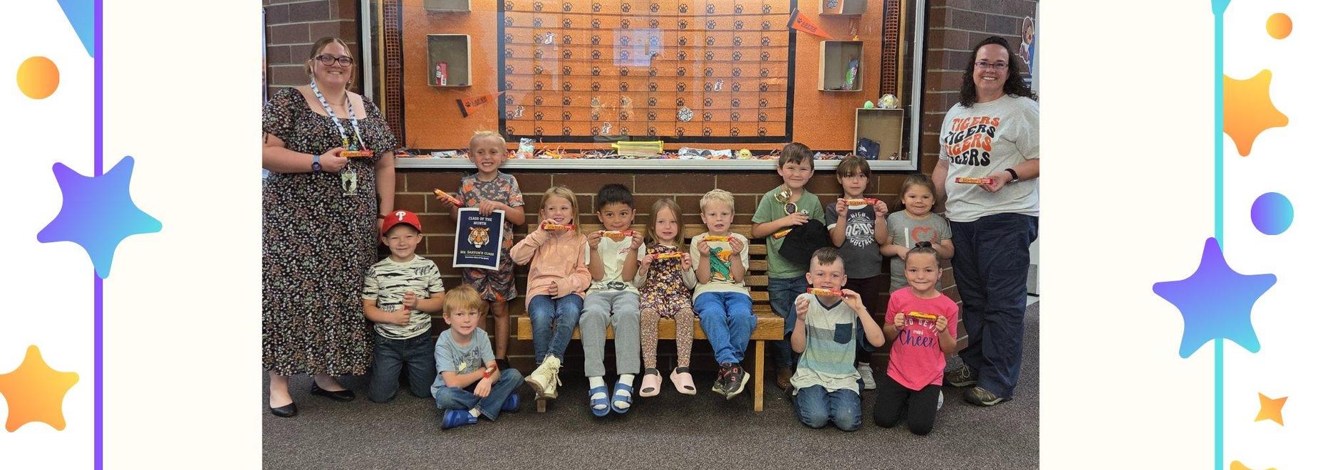 Group of children and adults posing with awards and certificates in a school setting.