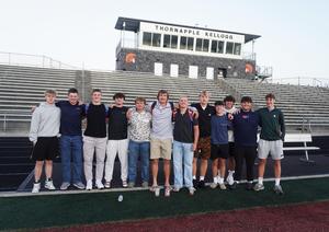 A group of students stand on the field for a photo.