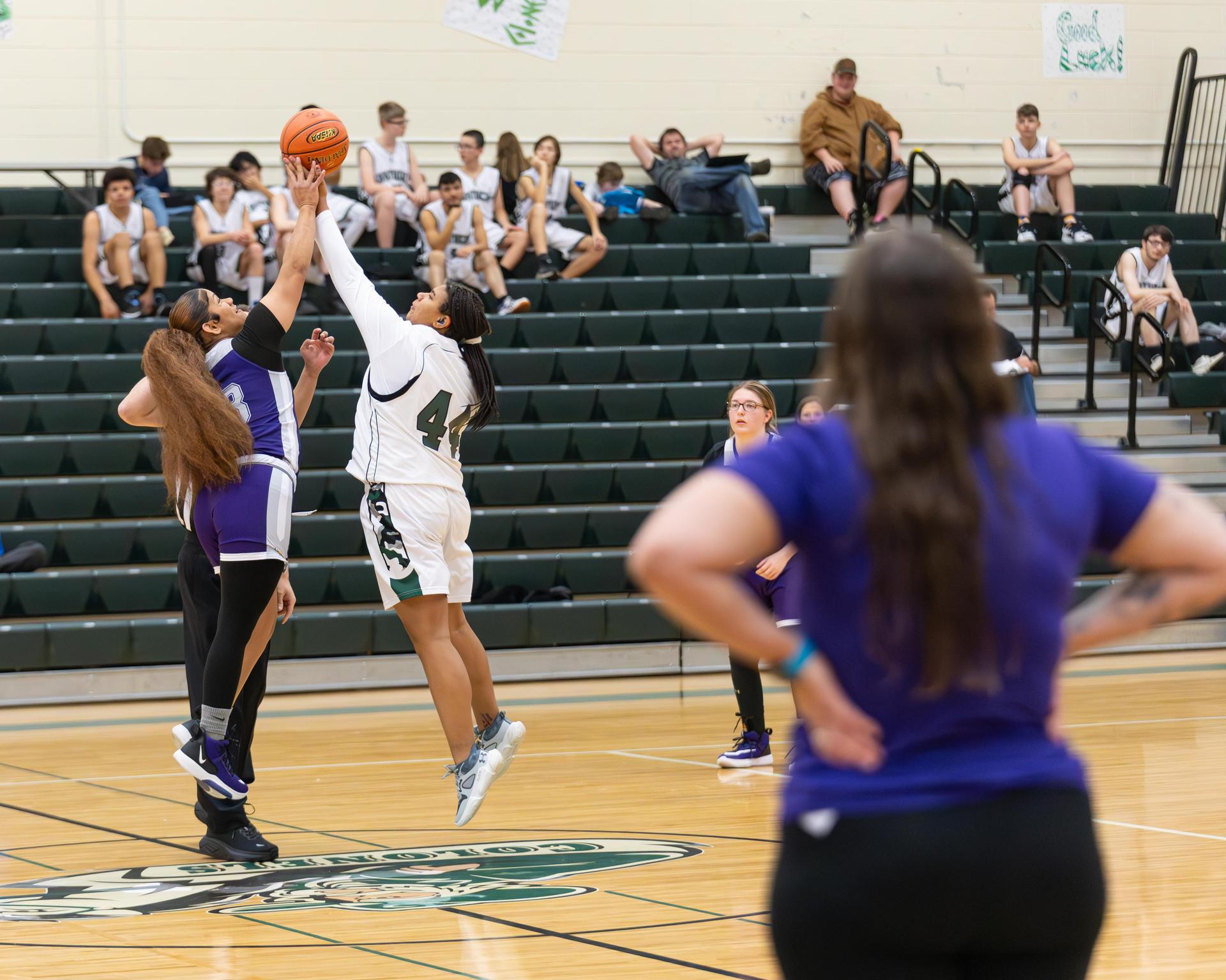 Showing the back of the girls coach as she watches the tip off of the game 