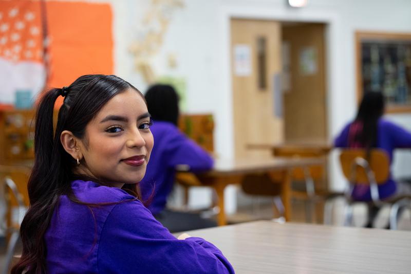 Student sitting at desk smiling at camera
