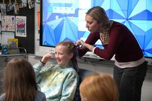 A student gets her hair braided by a hair sytlist.