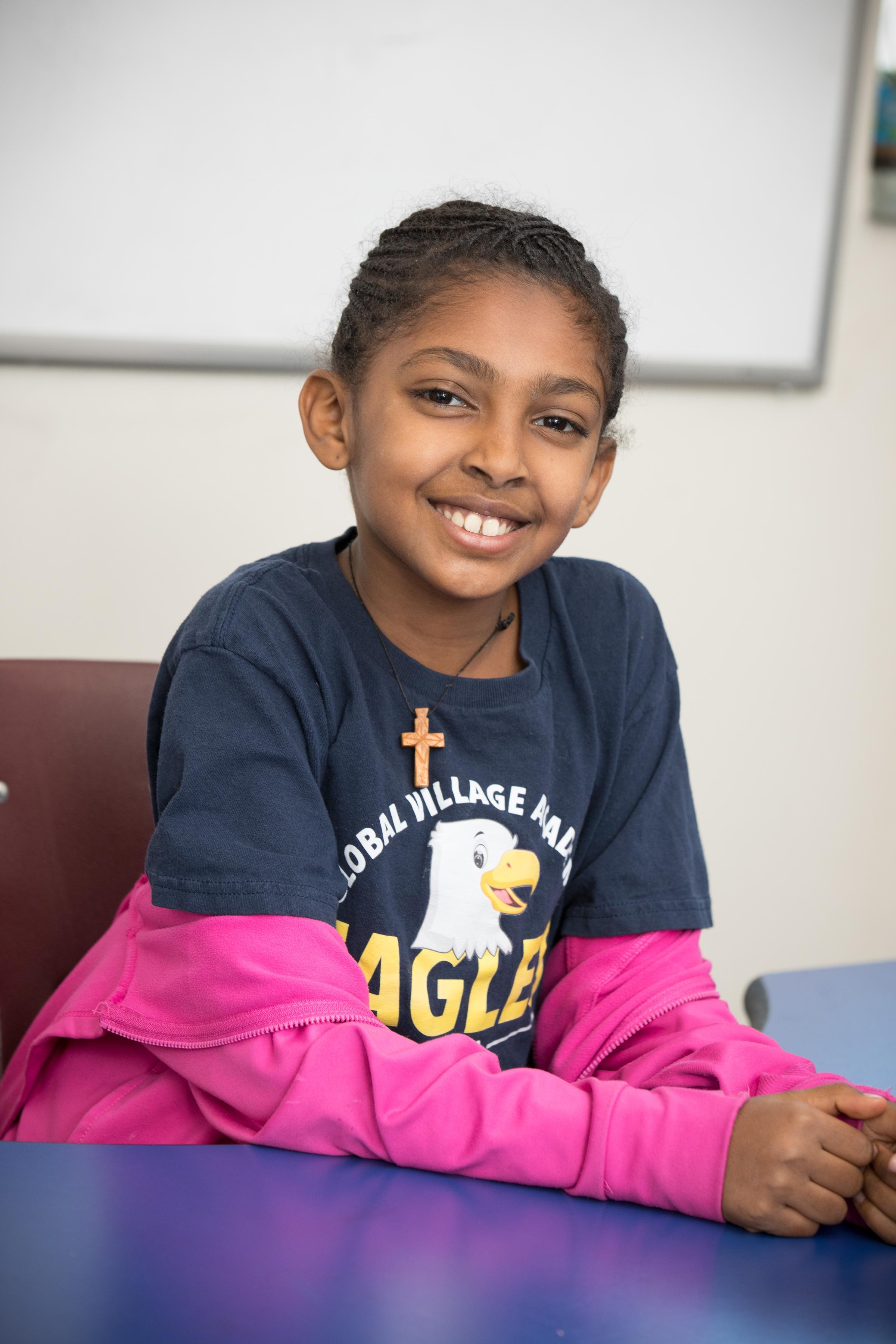 little girl smiling in a classroom wearing GVA shirt