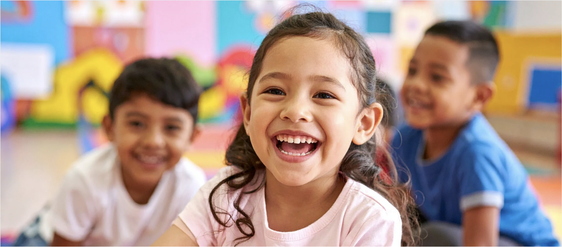 A young girl laughs in a brightly colored classroom