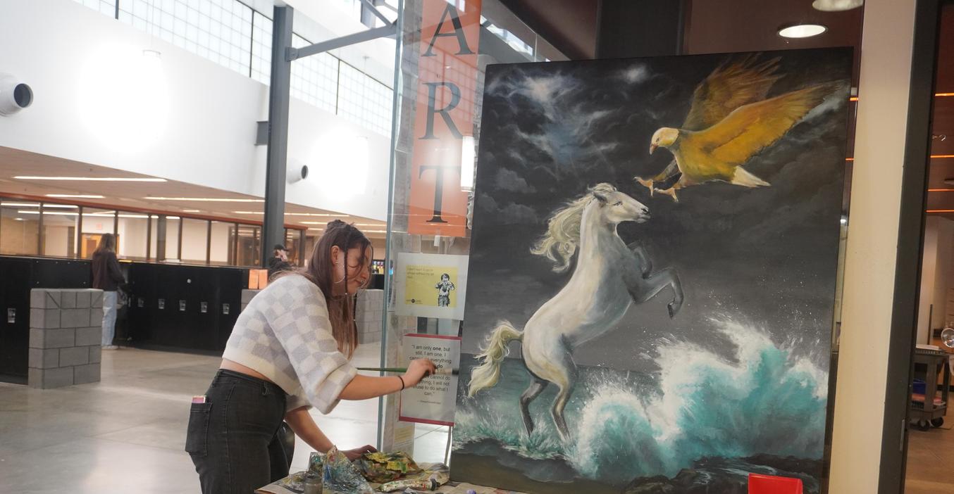 An art student puts the finishing touches on one of her paintings.