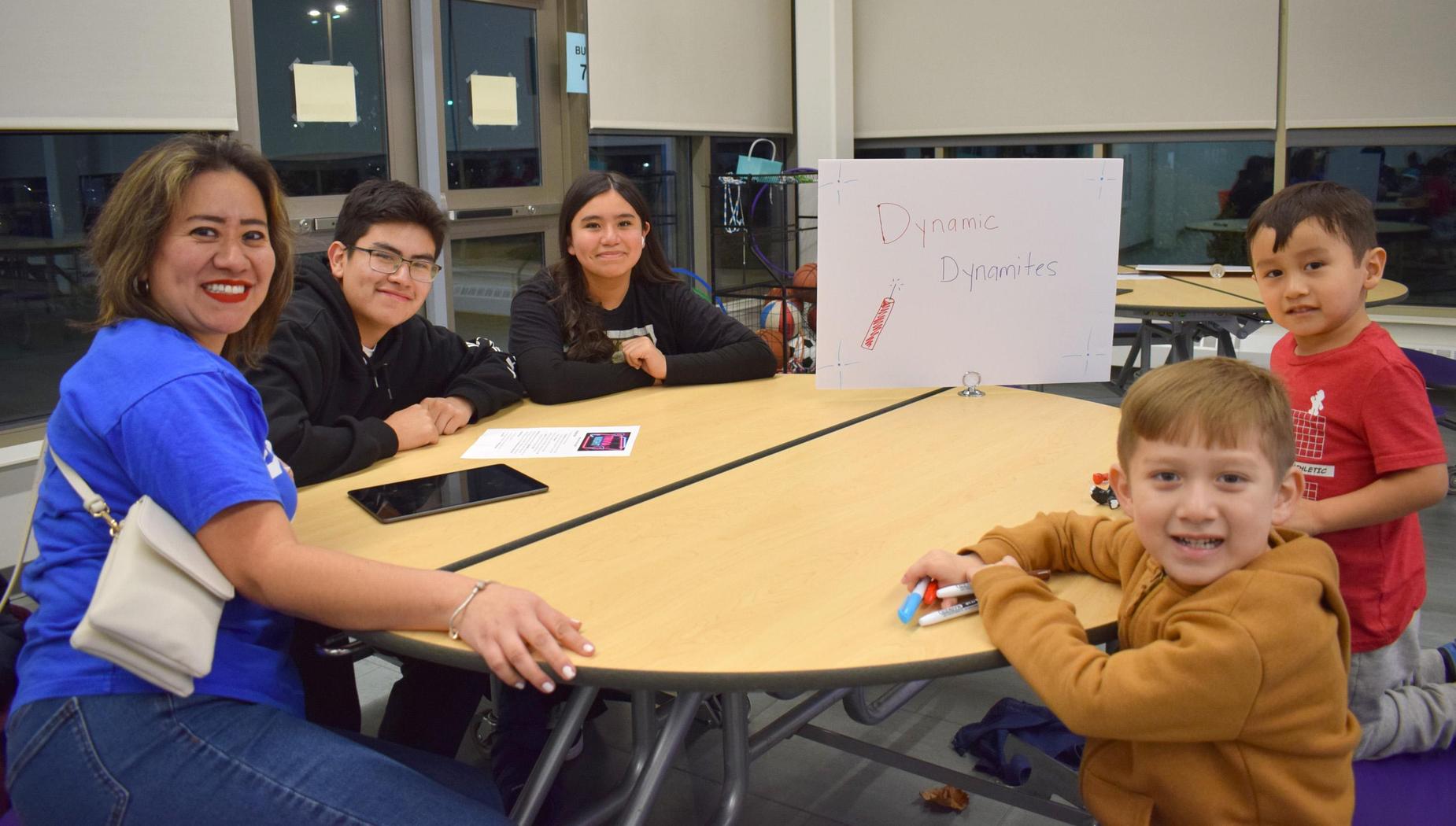 A family group seated at a table with signs and drawings, enjoying their time together.