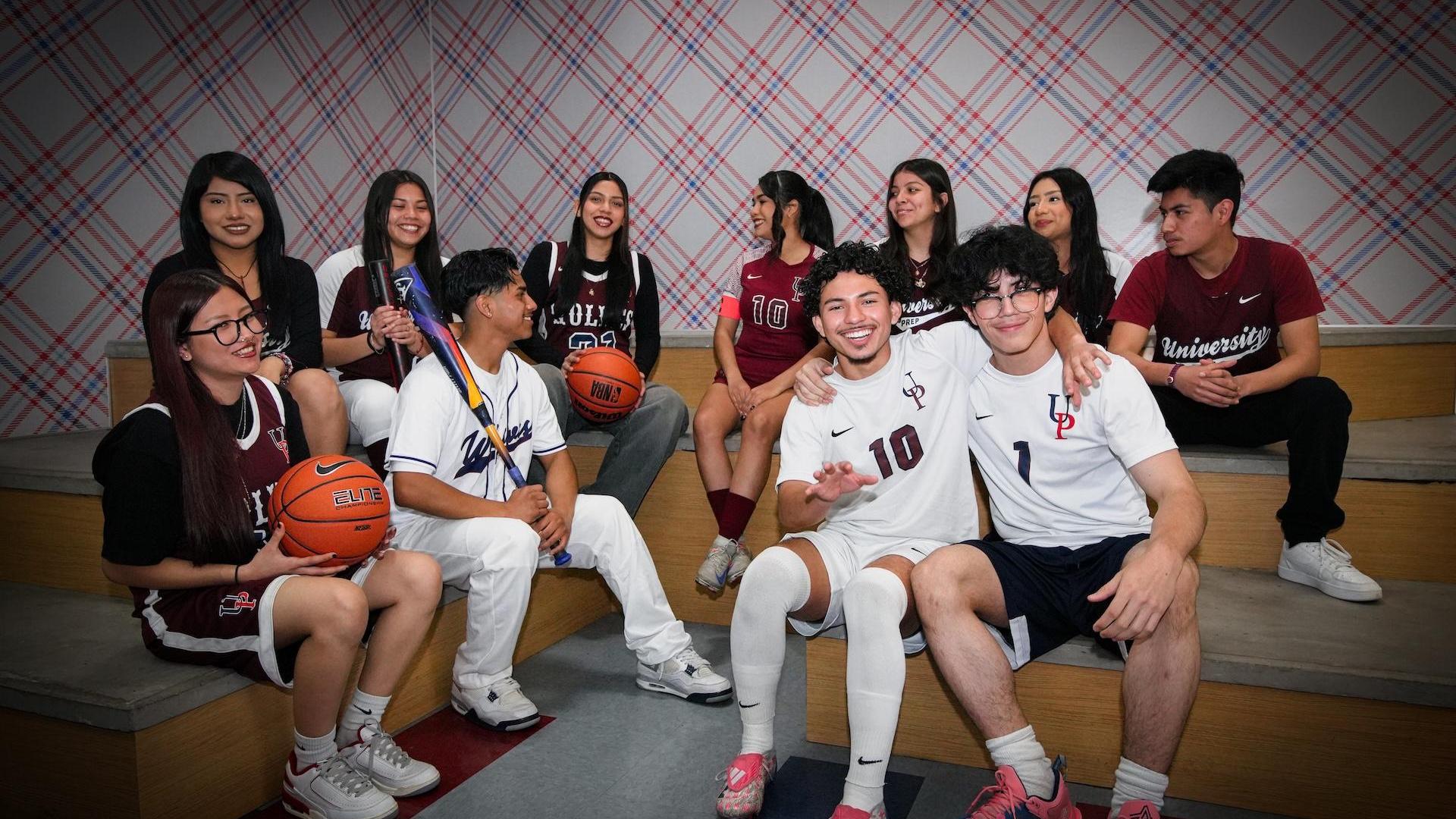 A group of students in basketball uniforms posing together on steps.